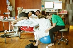 Chicago birth photography - doula, father and laboring mother on birth ball